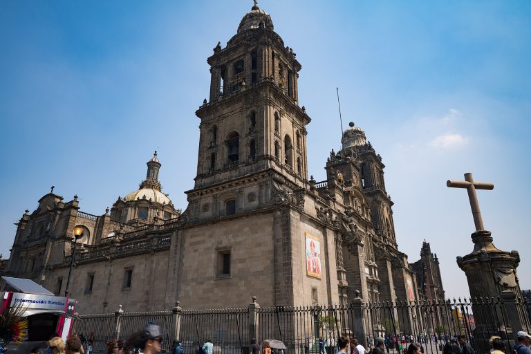 A Catedral Metropolitana da Cidade do México, com uma cruz de pedra em primeiro plano